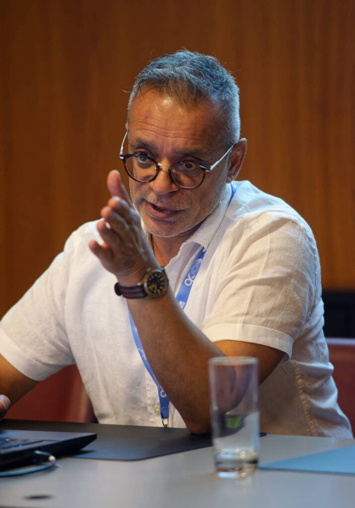 image of Nick Juty at a table communicating to someone in the audience